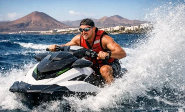 Tourist riding jet ski in Lanzarote Atlantic Ocean waters thrilling watersports activity in Puerto del Carmen