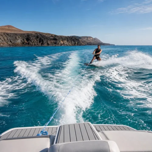 View from the tow boat toward a wakeboarder near the volcanic coast